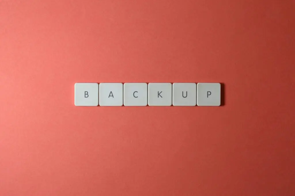Free Close-up of keyboard keys spelling 'BACKUP' placed on a coral-colored surface. Stock Photo