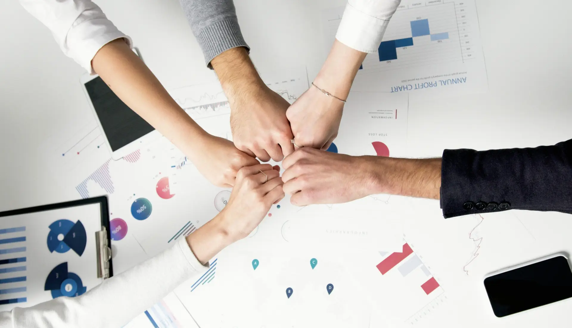 How-Smart-IT-Boosts-Employee-Morale-and-Keeps-Your-Best-People-scaledjpg • Managed IT Services and Cybersecurity Provider in Singapore. Free Colleagues celebrate success with a fist bump over financial charts depicting teamwork and unity. Stock Photo