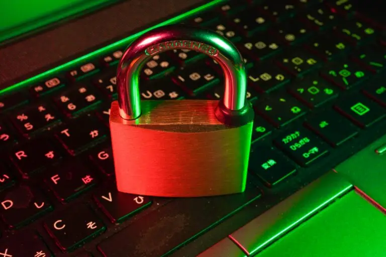 Metal padlock resting on a dark laptop keyboard, illuminated with red and green neon lighting to convey cybersecurity and data protection.
