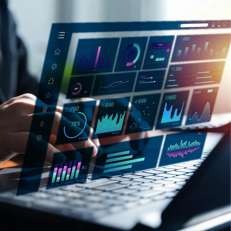 Futuristic holographic dashboards showing charts and graphs projected above a laptop keyboard as someone interacts with data analytics tools.